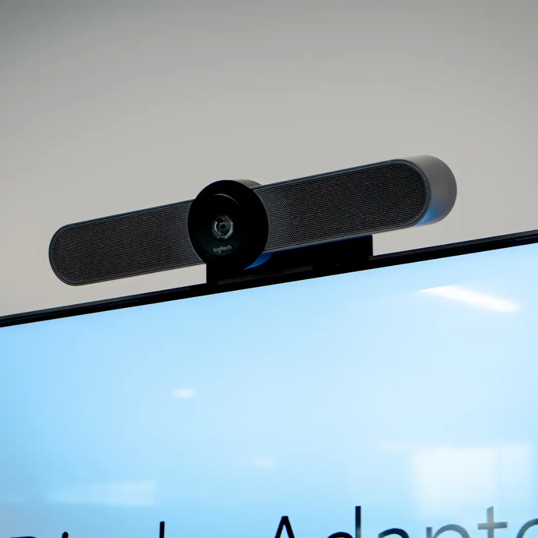 Logitech webcam and sound bar mounted to TV screen in corporate office.