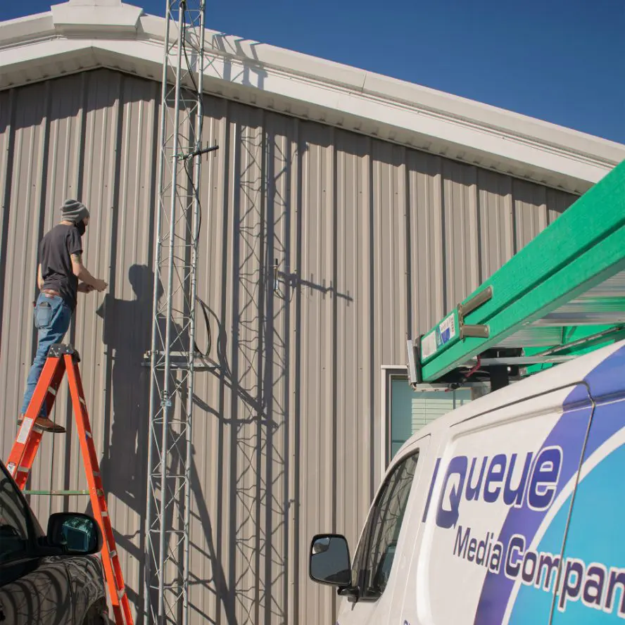 Exterior building cabling installation with technician and truck.
