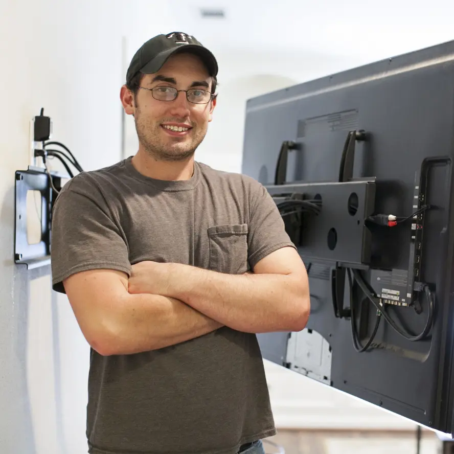 IQueue Media professional install team member behind TV installation with cabling.