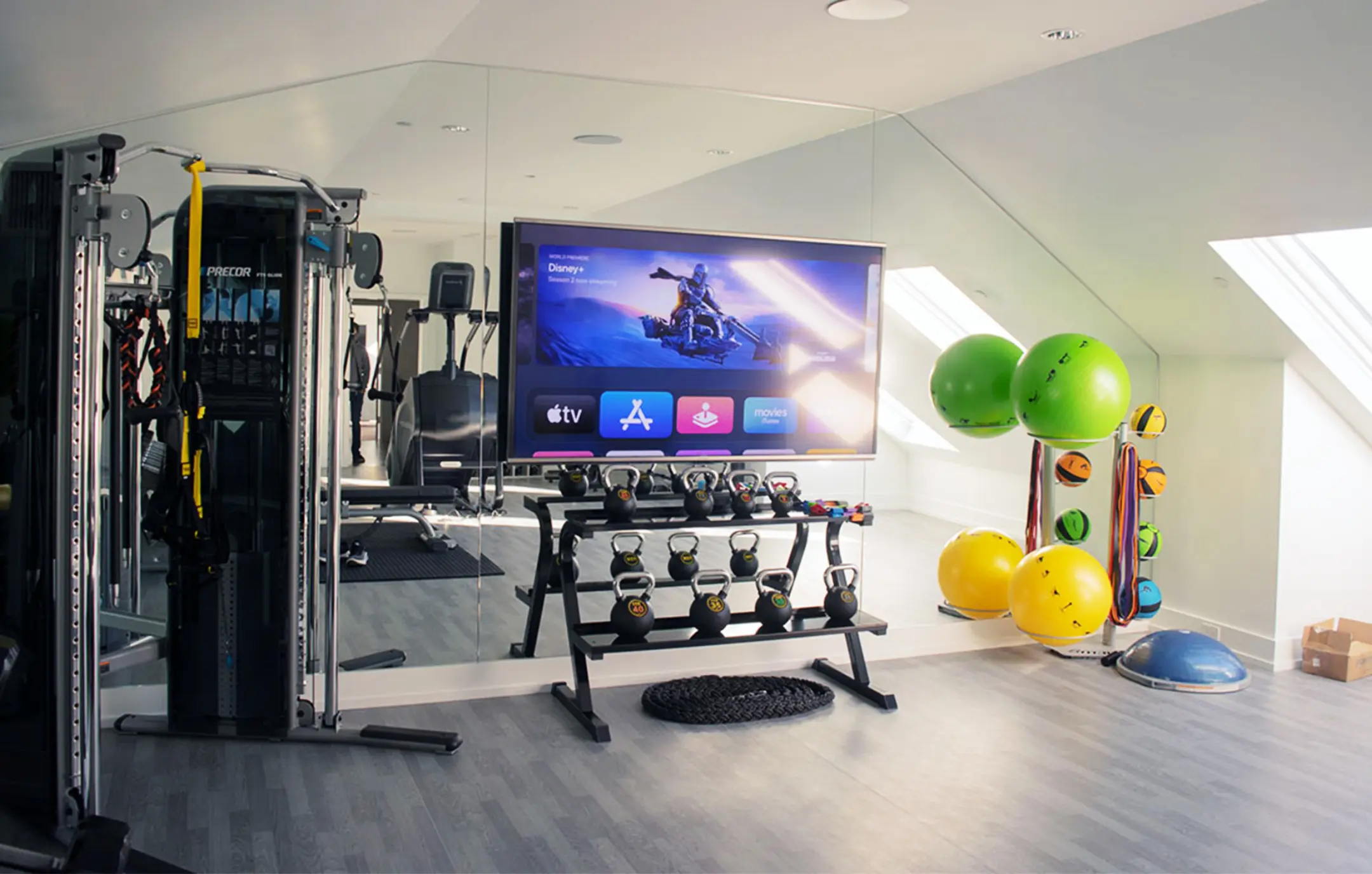 In-home gym with TV screen installed over mirrored wall.
