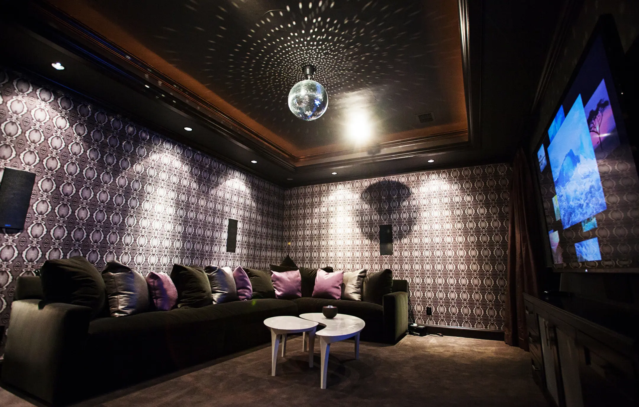 High-end home theater with AV installation, wallpapered walls, sofa, surround sound and disco ball lighting.