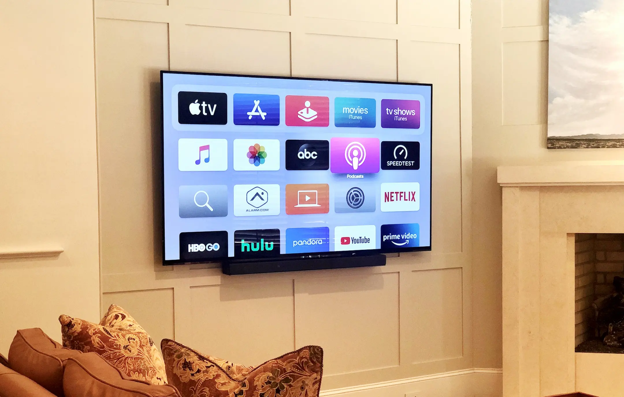 Television installation with sound bar on white paneled living room wall.