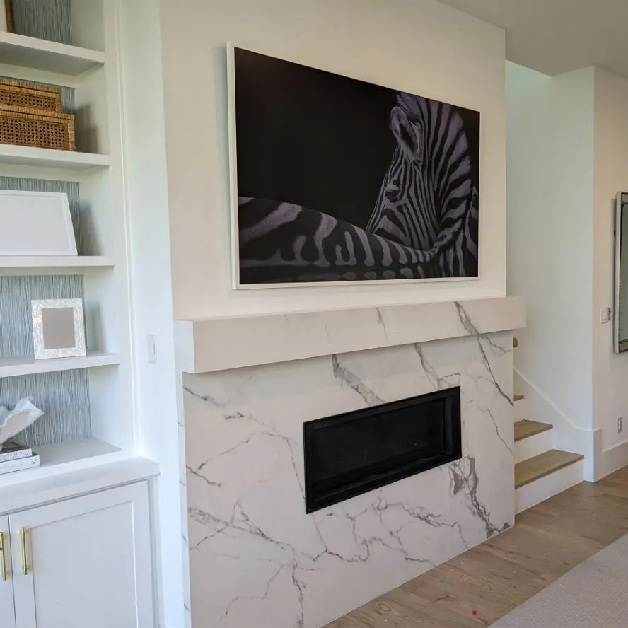Samsung Frame TV professionally installed above marble fireplace.