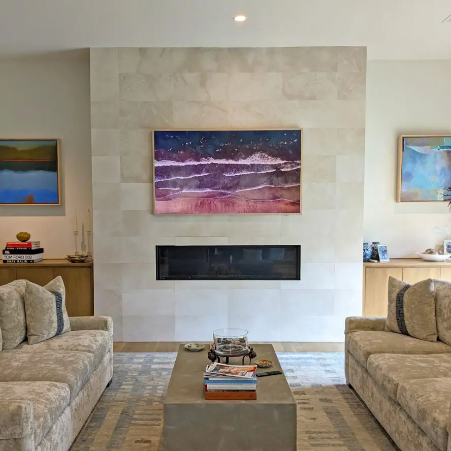 Samsung Frame TV installed above fireplace on modern stone wall. 