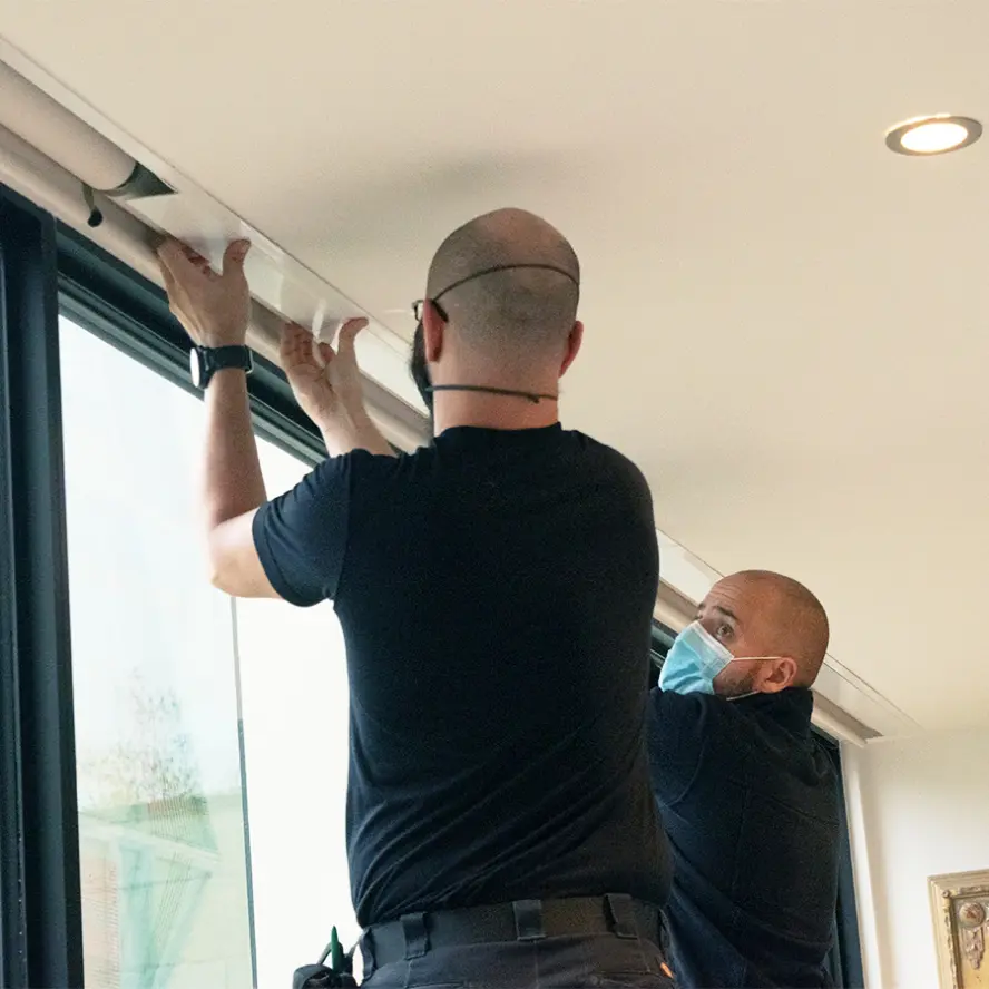 Two team members installing automated shades in home.