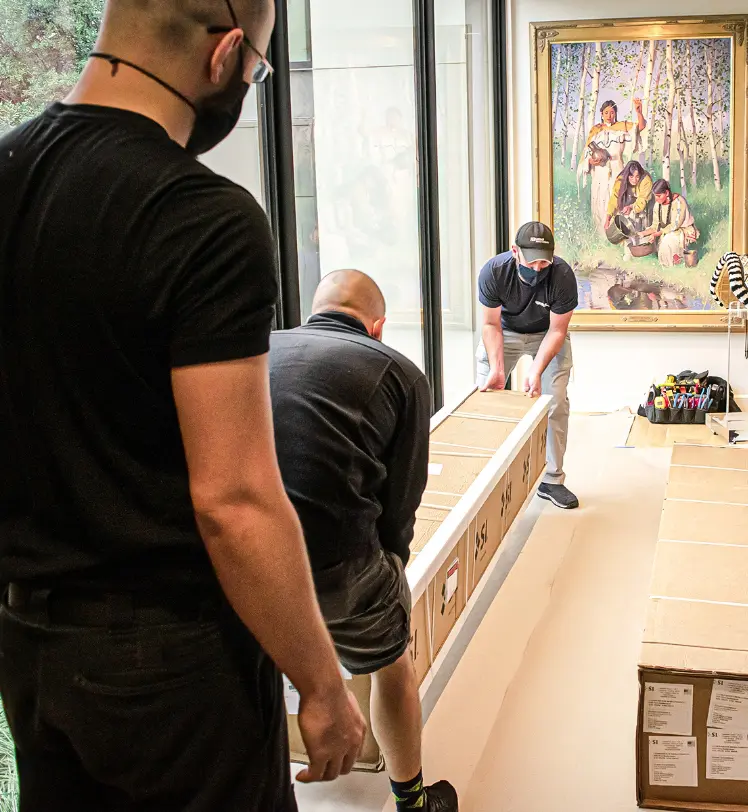 IQueue team members moving electronic boxes in home hallway.